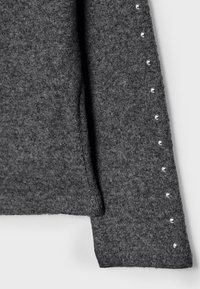 Sivi pulover iz filca z teksturirano površino, s pravim krojem in okrasnimi srebrnimi zakovicami ob levi rokav.