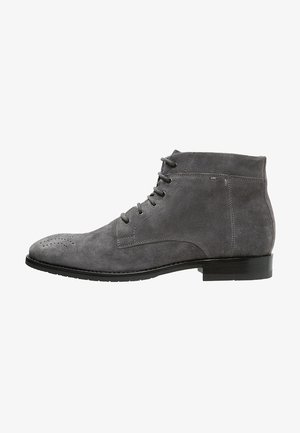 Stivaletto in suede grigio con lacci, perforazioni brogue sulla punta e suola bassa nera.