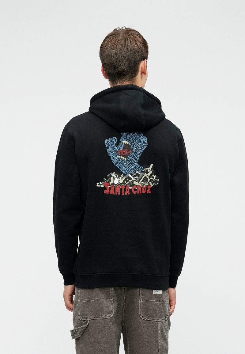 Crna dukserica s šarenim grafičkim prikazom plave ruke s ustima, preko pozadine stiliziranih oblika, sa tekstom "SANTA CRUZ" ispod.