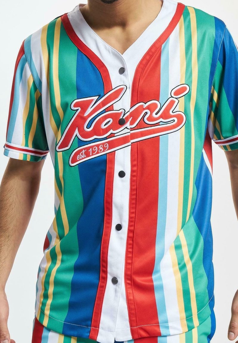 Buntes Kurzarmtrikot mit vertikalen Streifen in Grün, Blau, Rot und Gelb. Vordere Knöpfe mit weißem "Kani"-Logo.