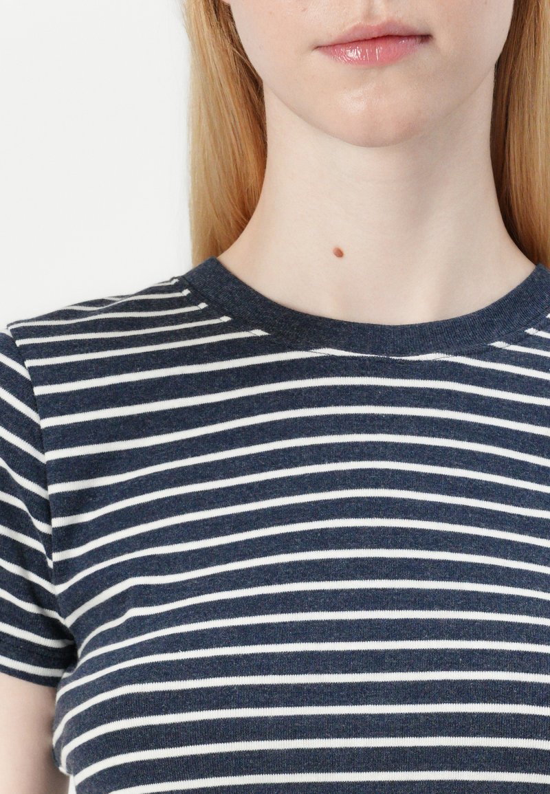 Marineblaues und weißes gestreiftes T-Shirt mit Rundhalsausschnitt, kurzen Ärmeln und einer weichen Textur. Nahaufnahme, die sich auf das Muster des Stoffes konzentriert.