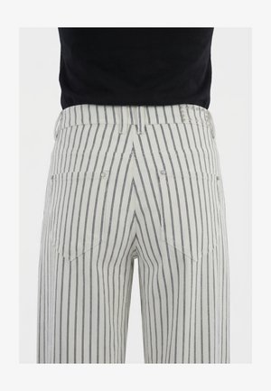 Pantaloni bianchi con sottili strisce verticali nere visti da dietro, con due tasche con rivetti e una cintura con passanti.