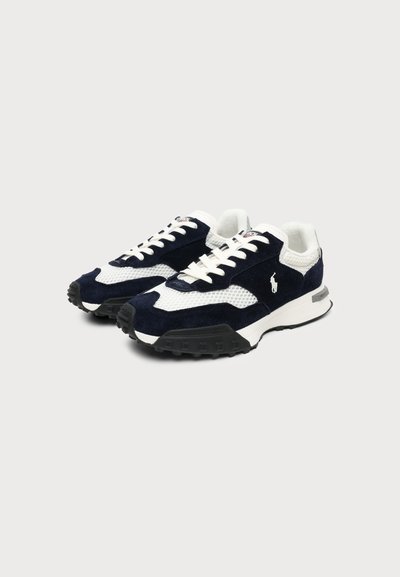 Ζευγάρι ασπρόμαυρα sneakers με κορδόνια, υφασμένα πέλματα και μικρό λογότυπο αλόγου στο πλάι, εμφανιζόμενα σε ουδέτερο φόντο.