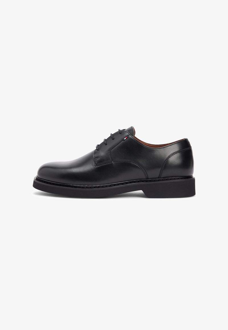 Chaussure habillée noire en cuir à lacets avec un talon bas, un bout arrondi et une doublure intérieure marron, présentée de profil sur fond blanc.