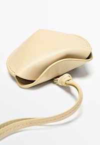 Borsa a mano in pelle beige con texture liscia, silhouette curva e una tracolla sottile. Presenta bordi cuciti e un design con apertura superiore.