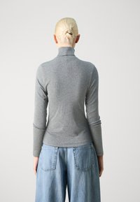 Szürke, hosszú ujjú garbó felső, bordázott anyagból készült, deréknál fitneszes, világoskék, bő szárú farmernadrággal, hátsó zsebekkel.