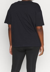 Camiseta de algodón negra con mangas cortas, un corte relajado y un escote redondo, que presenta costuras mínimas y sin acentos o patrones destacables.