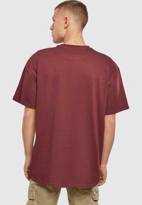 Bordeaux bomulds T-shirt med korte ærmer, rund hals og en afslappet pasform. Let længere bagklip, ensartet tekstur, ingen synlige mønstre eller logoer.