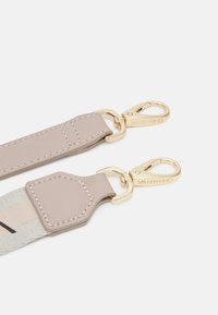 Sangle Valentino en beige clair avec des finitions dorées. Présente une texture lisse, des détails cousus et des attaches à clip pour une utilisation sécurisée.
