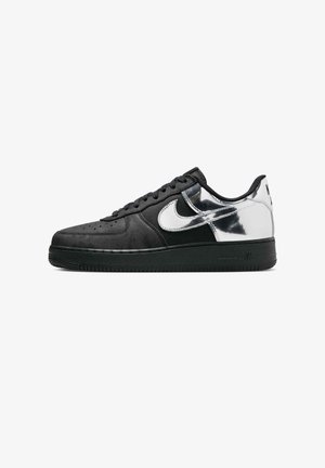 Baskets basses noires avec talon et panneau latéral argent métallisé, virgule Nike blanche et semelle en caoutchouc noire.