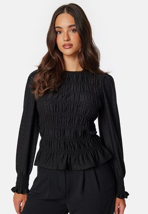 Top nero arricciato con maniche lunghe, tessuto testurizzato, scollatura rotonda e orlo arricciato. Presenta dettagli sottili per un interesse visivo aggiuntivo.
