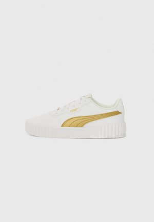 White sneaker with textured rubber sole, yellow accent stripes, gold eyelets, and a smooth synthetic upper material. Low-top design.