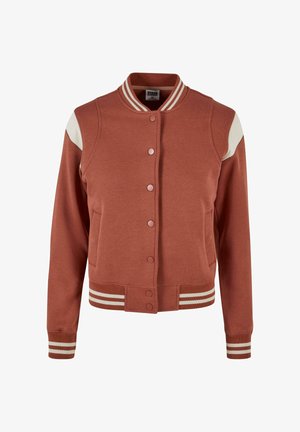 Giacca bomber color ruggine con dettagli bianchi sulle spalle, chiusura con bottoni, polsini e orlo a costine con strisce bianche. Tessuto dalla texture liscia.