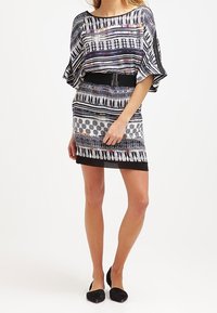 Sukienka z krótkim rękawem, wykonana z materiału w wielokolorowy wzór w odcieniach czerni, bieli i niebieskiego, z wcięciem w talii i prostą spódnicą.