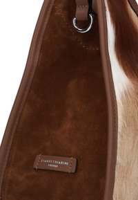 Bruine suède handtas met leren accenten, voorzien van een unieke vachtachtige textuur en een label met de tekst "GIANNI CHIARINI FIRENZE."