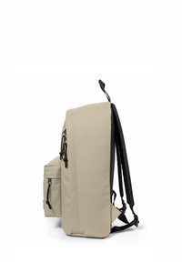 Beige selkäreppu, jossa on tilava pääosasto, etutasku, säädettävät hihnat ja tyylikäs muotoilu. Teksturoitu kangas mustilla yksityiskohdilla.