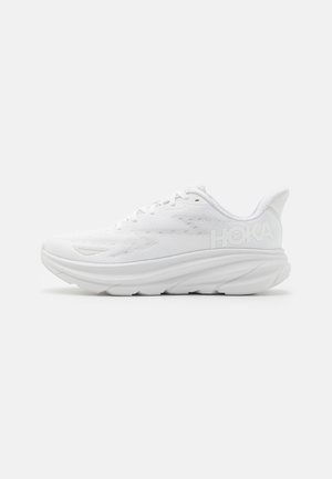 Zapatilla de running blanca con una parte superior de malla transpirable, suela acolchada, talón pronunciado y logotipo "HOKA" elevado en el lateral.