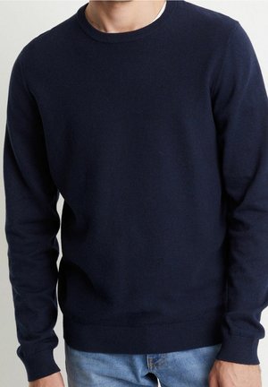 Marineblauwe gebreide trui met een ronde hals, lange mouwen, geribde manchetten en zoom. Soepele textuur, minimalistisch ontwerp zonder patronen.