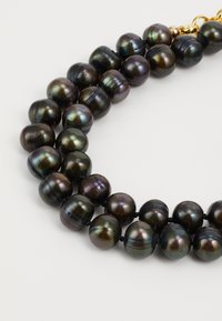 Collier de perles en fil noir et gris présentant des perles rondes et brillantes avec une brillance variée, entrecoupées d'un fermoir en or.