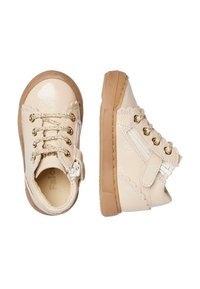 Scarpe per bambini color crema con lacci dorati, cerniera laterale, fascia in Velcro e suole in gomma marrone, mostrate da viste frontali e laterali.