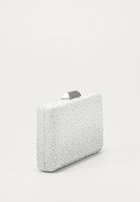 Biała prostokątna kopertówka wykonana z gładkiego materiału, ozdobiona srebrnymi ćwiekami, z metalowym zapięciem na górze i teksturowanym wzorem.