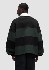 Bluza crewneck w kolorze czarnym, ciemnozielonym i zielonym w poziome paski. Charakteryzuje się białym kołnierzykiem, luźnym krojem i teksturowanym materiałem.