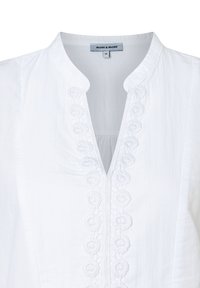 Weißes Blusenshirt mit V-Ausschnitt, das zarte bestickte Details entlang der Knopfleiste aufweist. Hergestellt aus leichtem Stoff mit einer weichen Textur.