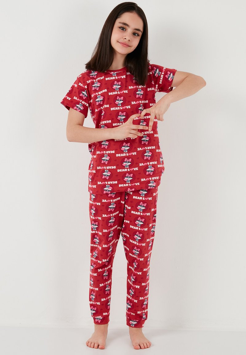 Röd pyjamasuppsättning med kortärmad topp och byxor, prydd med ett tecknat mönster och frasen "KÄRA KÄRLEK." Mjuk tyg, avslappnad passform.