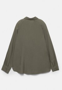 Chemise à manches longues vert olive avec poignets boutonnés, vue de dos, posée à plat sur un fond blanc.