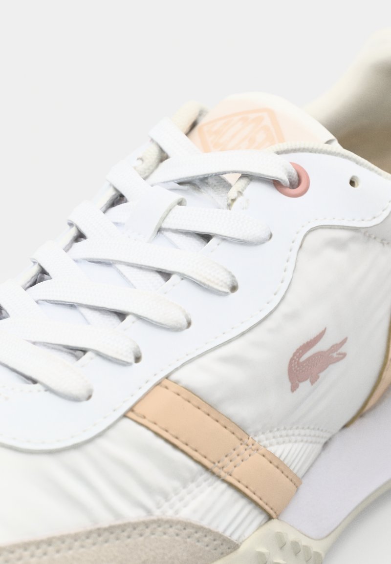 Weiße Sneaker mit strukturiertem Leder und Mesh, mit einem rosa Akzentstreifen und Logo. Schnürverschluss und gepolsterte Sohle hervorgehoben.