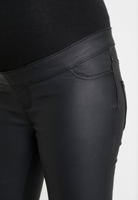 Svarta läderbyxor med en figursydd design. Har diskreta sömmar, en framficka och en slät yta.