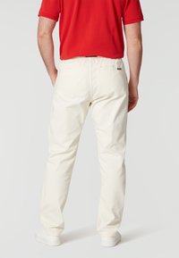 Vita bomullsshorts med elastisk midja, bakfickor och avslappnad passform, kombinerat med en röd polo t-shirt och vita sneakers.