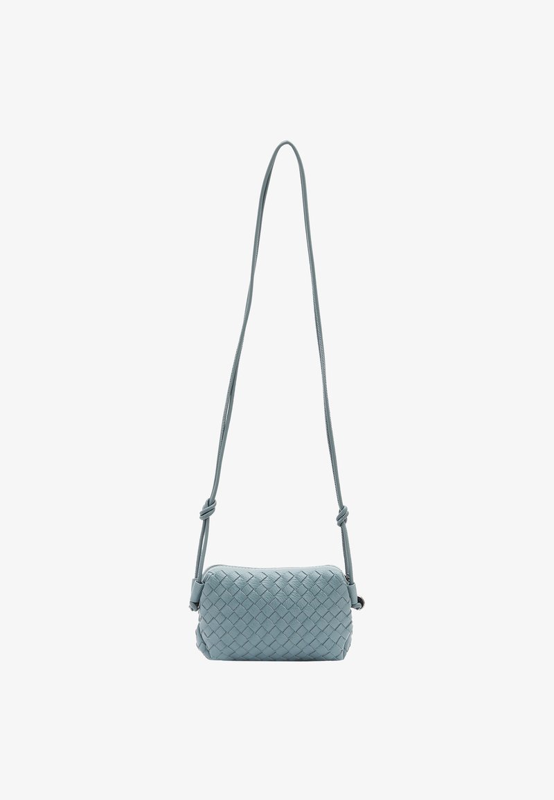 Valkoinen risteilylaukkua vaaleansinistä nahkaa, jossa on suorakulmainen muoto, pitkä säädettävä hihna ja vetoketjusulku.