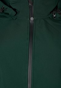 Groene jas met een gladde, matte textuur; centrale zwarte ritssluiting met knoopdetail; verstelbare trekkoorden aan de capuchon.