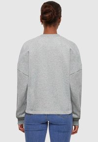 Grå sweatshirt med långa ärmar, ribbade muddarna och rundad halsringning. Mjuk textur, avslappnad passform och sydda detaljer på baksidan.