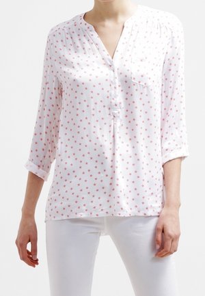 Witte blouse met een licht rood sterrenpatroon, een V-hals en omgeslagen mouwen met een knoopdetail. Gladde stoftextuur.