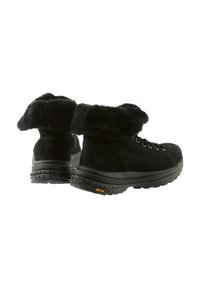 Svarta vinterstövlar med tjocka gummisulor från Vibram och mjuka pälskragar, visade från baksidan och sidan på vit bakgrund.