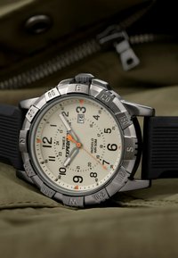 Orologio Timex Expedition con cassa in metallo argentato, cinturino in gomma nera, quadrante crema, numeri neri, dettagli arancioni e display della data.