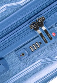 Blauer Koffer mit gebürsteter Optik, doppelten Metallreißverschlüssen, einem TSA-Schloss und einem Zahlenschloss mit drei Scheiben.