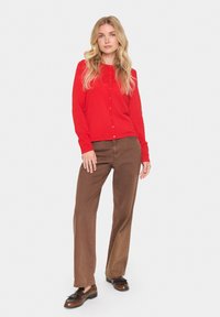 Rode cardigan met lange mouwen en knopen, gecombineerd met bruine rechte broek en bruine schoenen. Gladde textuur, casual pasvorm.