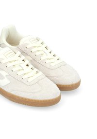 Zapatillas de ante beige con cordones crema, parte superior texturizada, suela de goma y detalle del logo cerca del talón. Forro interior suave.
