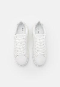 Sneakers bianchi in pelle con lacci piatti, punta rotonda, superficie liscia e design minimalista. Marchio "PIER ONE" sulla linguetta.