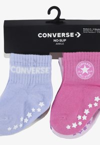Világos lila és rózsaszín boka zoknik, bordázott mintával, csillag mintákkal a talpán, és fehér "CONVERSE" logóval.