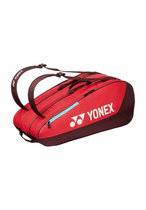 Bolsa deportiva Yonex roja y marrón con compartimentos dobles, correas para el hombro y un bolsillo lateral con cremallera.