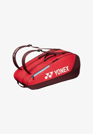 Bolsa deportiva Yonex roja y marrón con compartimentos dobles, correas para el hombro y un bolsillo lateral con cremallera.