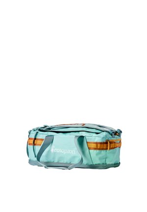 Bolsa de viaje azul claro con detalles en naranja, asas laterales y compartimento con cremallera en el frente, con la marca "cotopaxi" en el panel frontal.