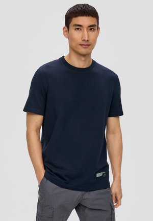 Camiseta de manga corta azul marino con un tejido texturizado, cuello redondo y una pequeña etiqueta en la parte inferior izquierda.