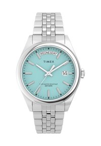 Montre Timex avec un cadran bleu clair, un boîtier en acier inoxydable argenté et un bracelet. Dispose d'un affichage du jour et de la date, de mains lumineuses et d'une résistance à l'eau.