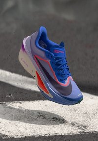 Běžecká bota Nike Zoom Fly s modro-fialovým přechodem na svršku, oranžovými detaily a texturovanou podrážkou s lehkou konstrukcí.