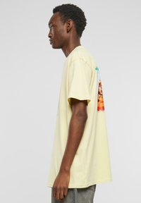 Yellow cotton t-shirt with short sleeves, featuring a graphic print on the back. Relaxed fit with a rounded neckline and visible stitching.